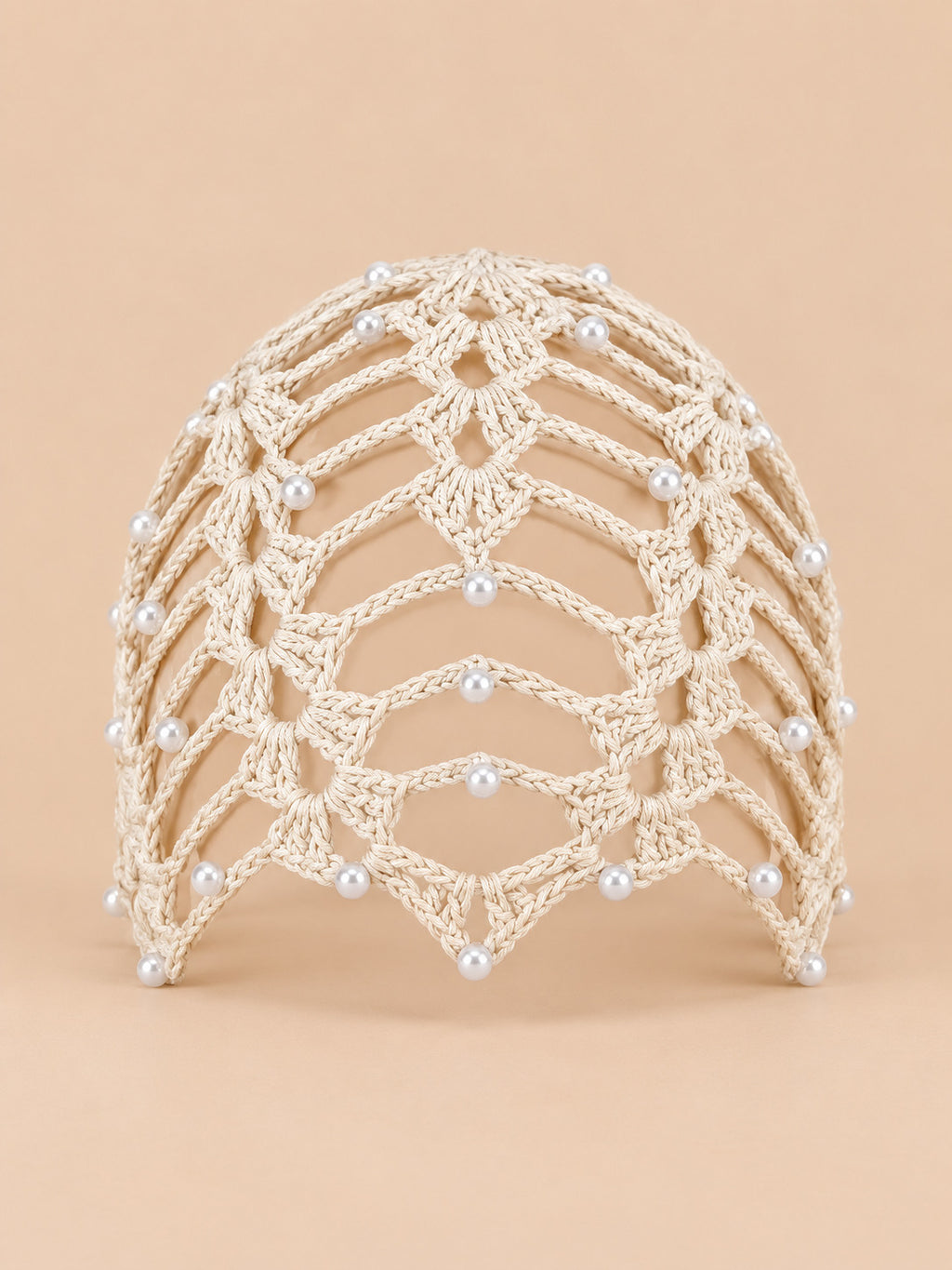 Bonnet bandana femme beige au crochet ajouré perlé, vue de face sur fond pêche sable