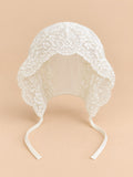 Béguin bébé fille en dentelle brodée, modèle 01, vue de face sur fond pêche sable