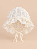 Béguin bébé fille en dentelle brodée, modèle 03, vue de face sur fond pêche sable