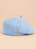 Béret ajouré style japonais bleu ciel, vue de face sur fond pêche sable