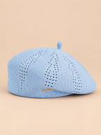 Béret ajouré style japonais bleu ciel, vue de face sur fond pêche sable