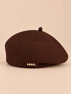 Béret ajouré style japonais marron, vue de face sur fond pêche sable