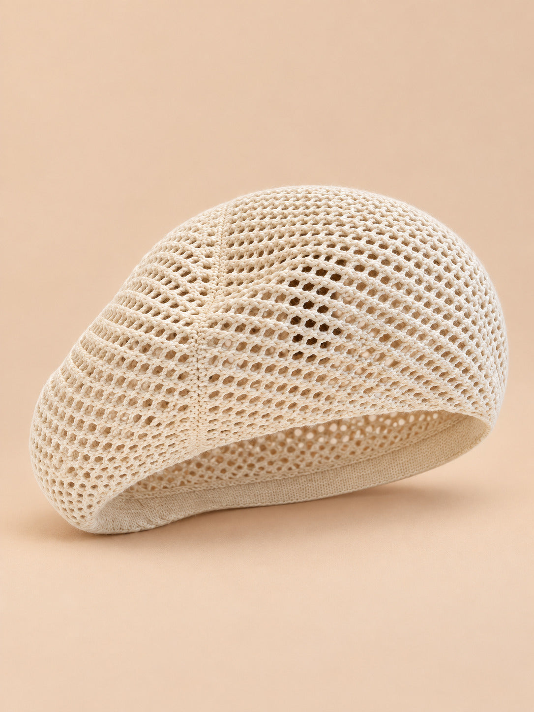 Béret d’artiste ajouré beige, vue de face sur fond pêche sable