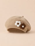 Béret bébé fille Café à fleurs en relief au crochet, vue de face sur fond pêche sable