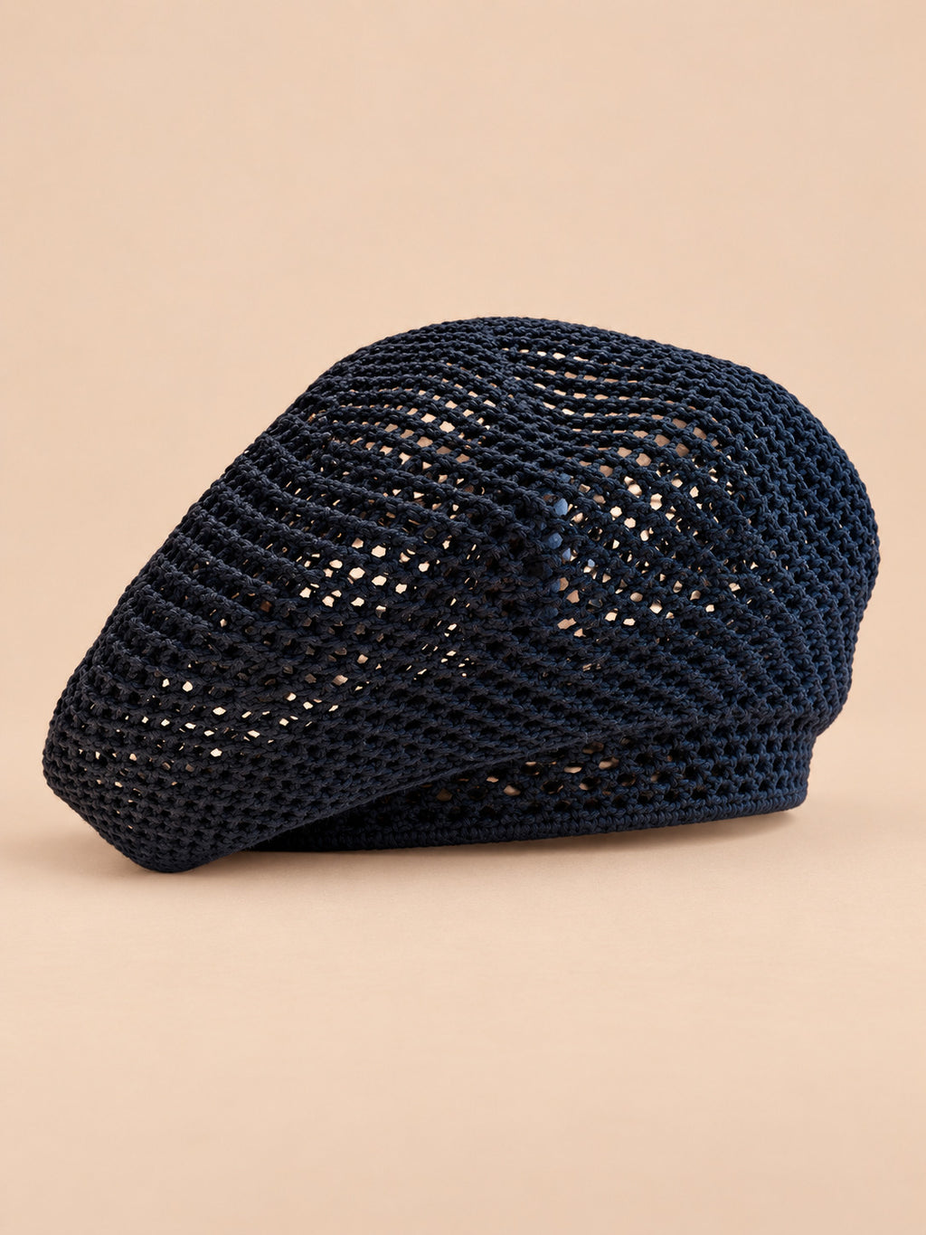Béret bibi résille bleu nuit, vue de trois quarts sur fond pêche sable