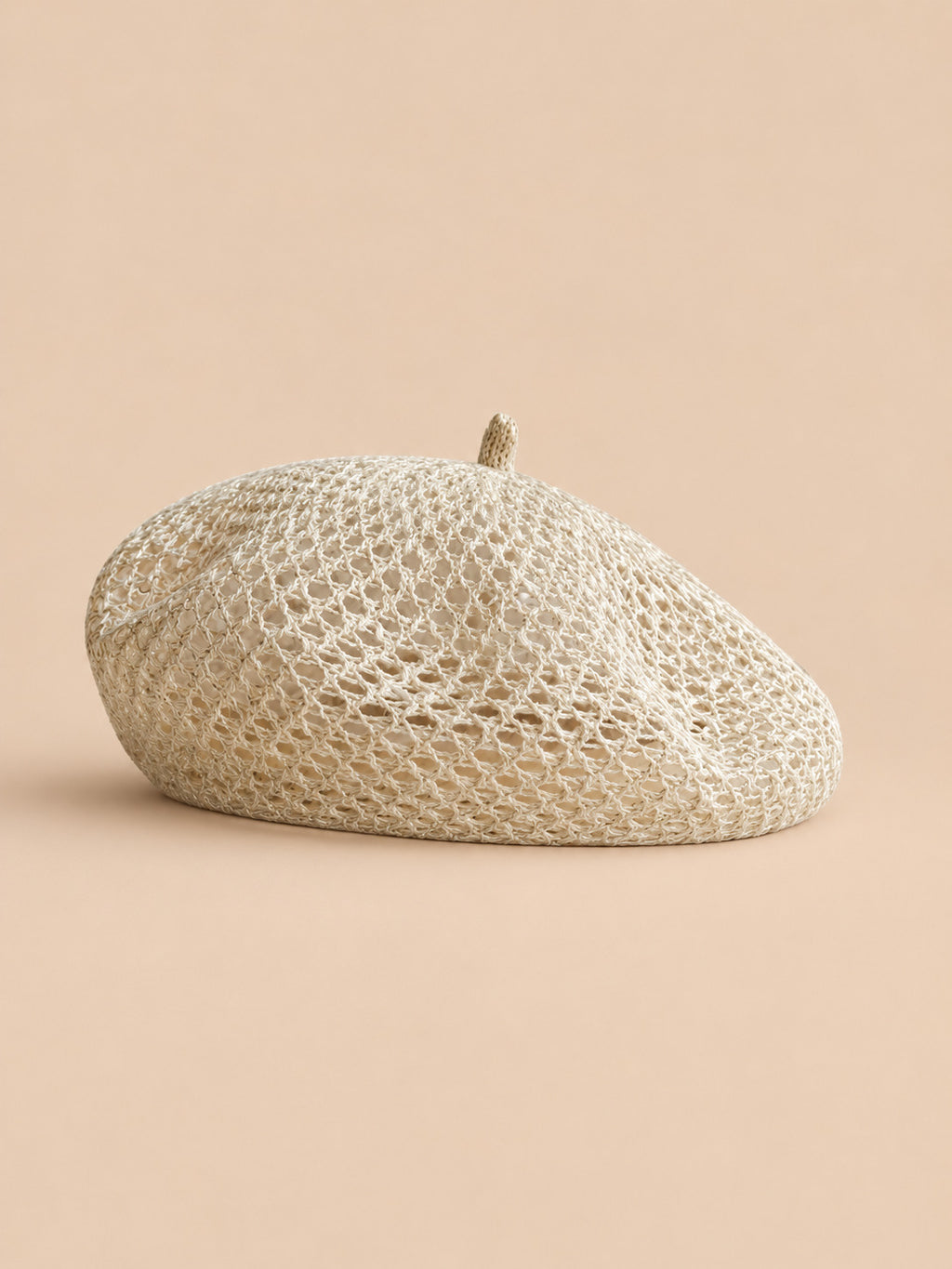 Béret citrouille ajouré beige, vue de face sur fond pêche sable