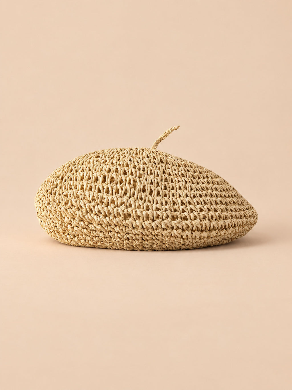Béret d’été en paille de papier beige, vue de face sur fond pêche sable