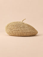 Béret d’été en paille de papier beige, vue de trois quarts sur fond pêche sable
