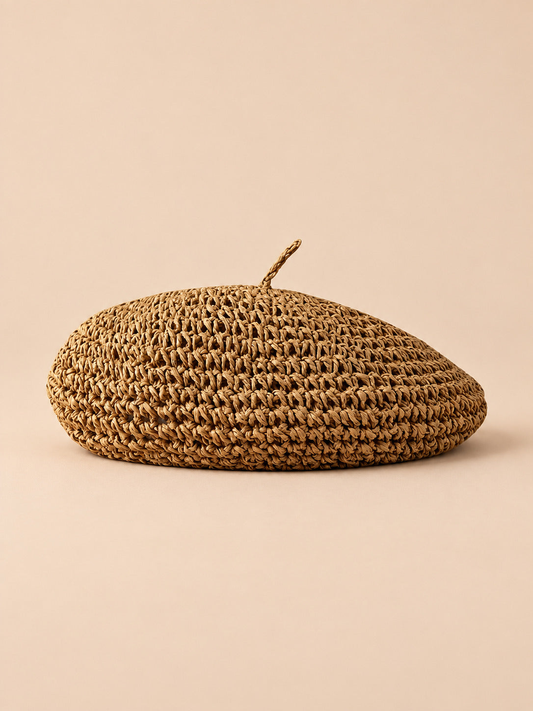 Béret d’été en paille de papier kaki, vue de face sur fond pêche sable