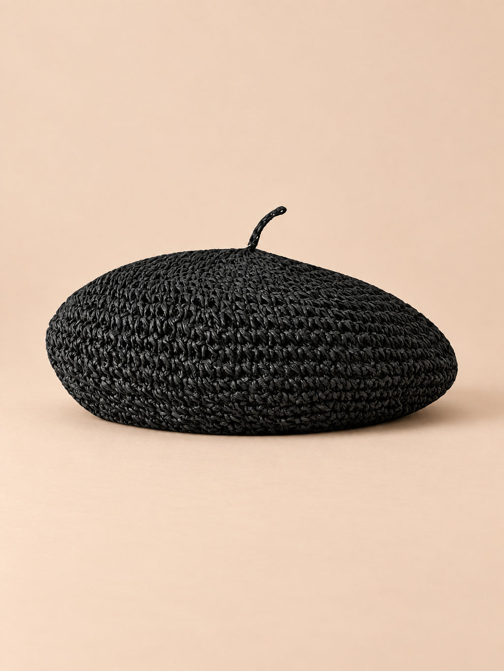 Béret d’été en paille de papier noir, vue de face sur fond pêche sable