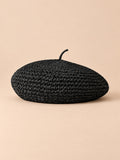 Béret d’été en paille de papier noir, vue de face sur fond pêche sable