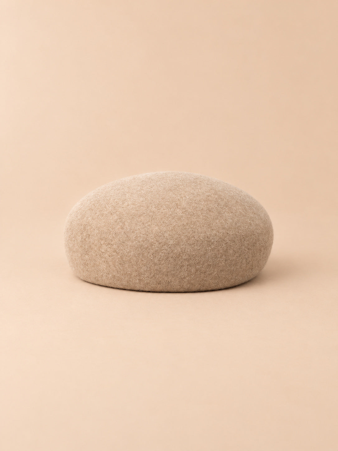 Béret femme en laine feutrée avoine, forme rond, vue de face sur fond pêche sable