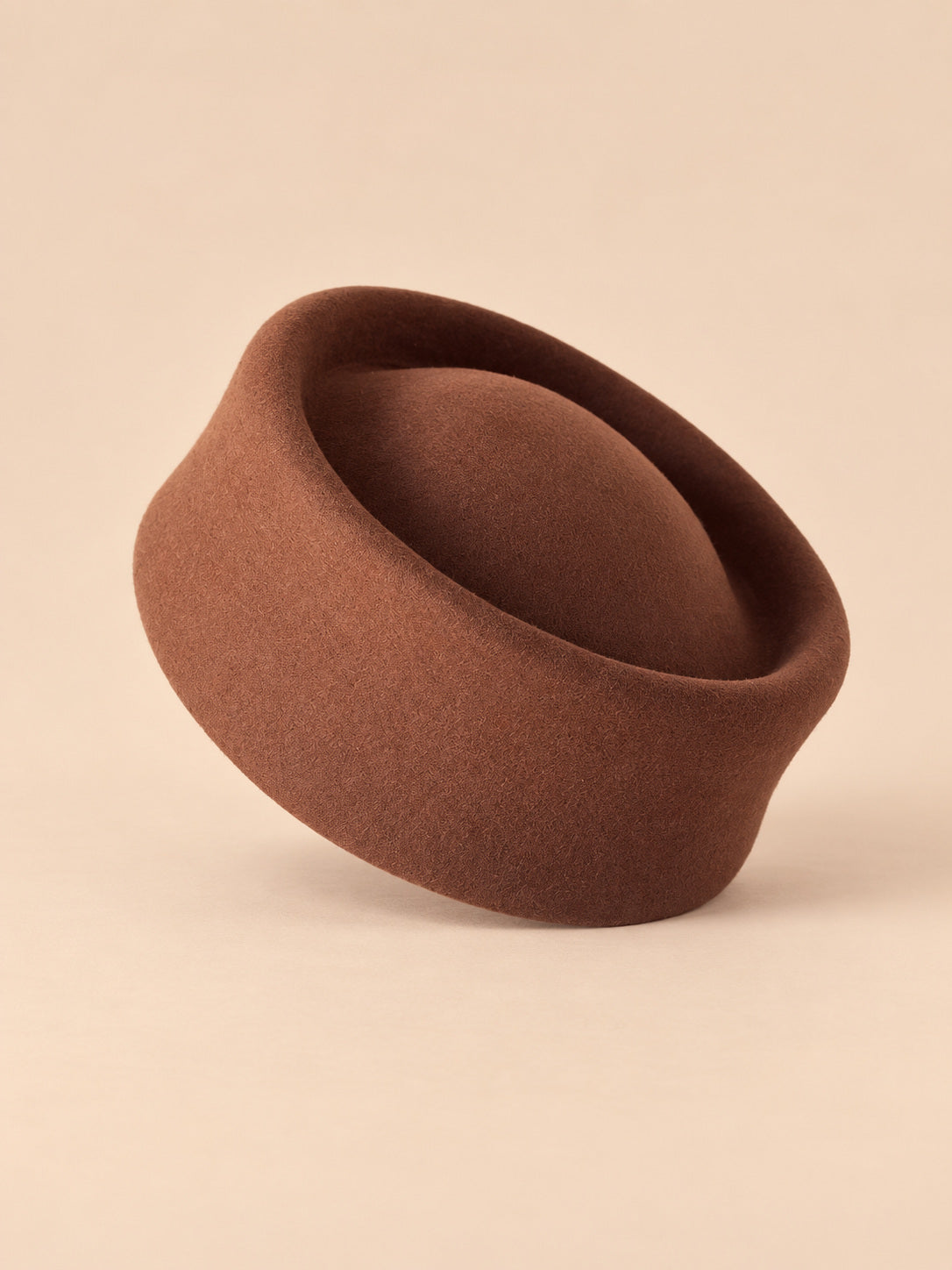 Béret femme en laine feutrée café, forme pork-pie, vue de face sur fond pêche sable