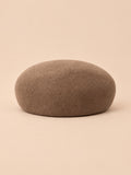 Béret femme en laine feutrée kaki, forme rond, vue de face sur fond pêche sable
