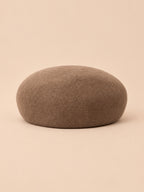 Béret femme en laine feutrée kaki, forme rond, vue de face sur fond pêche sable
