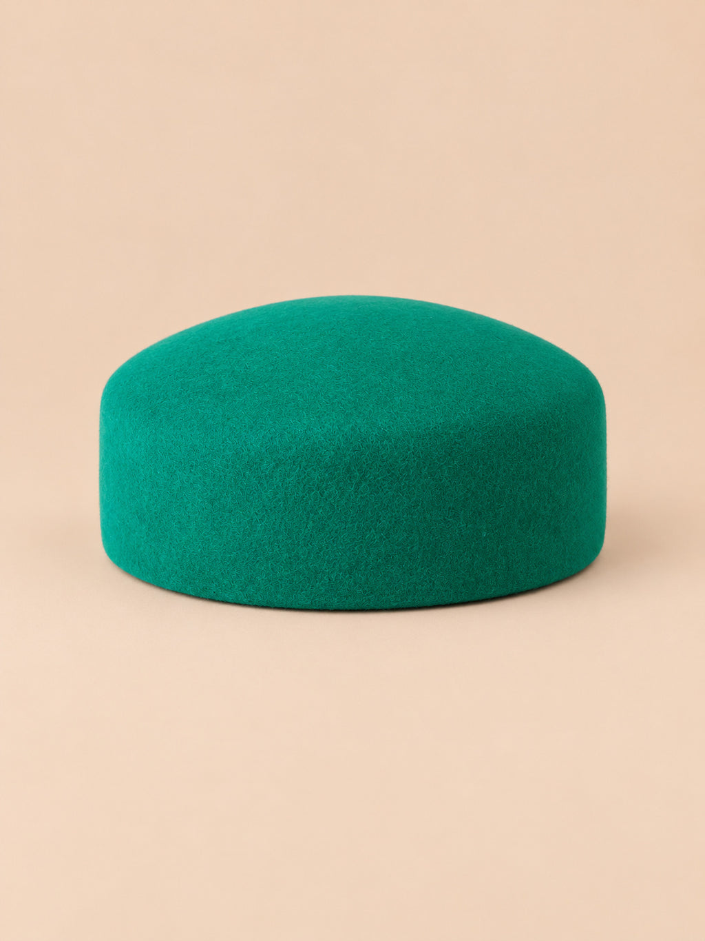 Béret femme en laine feutrée vert, forme plat, vue de face sur fond pêche sable