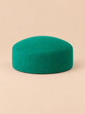 Béret femme en laine feutrée vert, forme plat, vue de face sur fond pêche sable