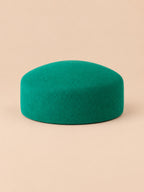 Béret femme en laine feutrée vert, forme plat, vue de face sur fond pêche sable