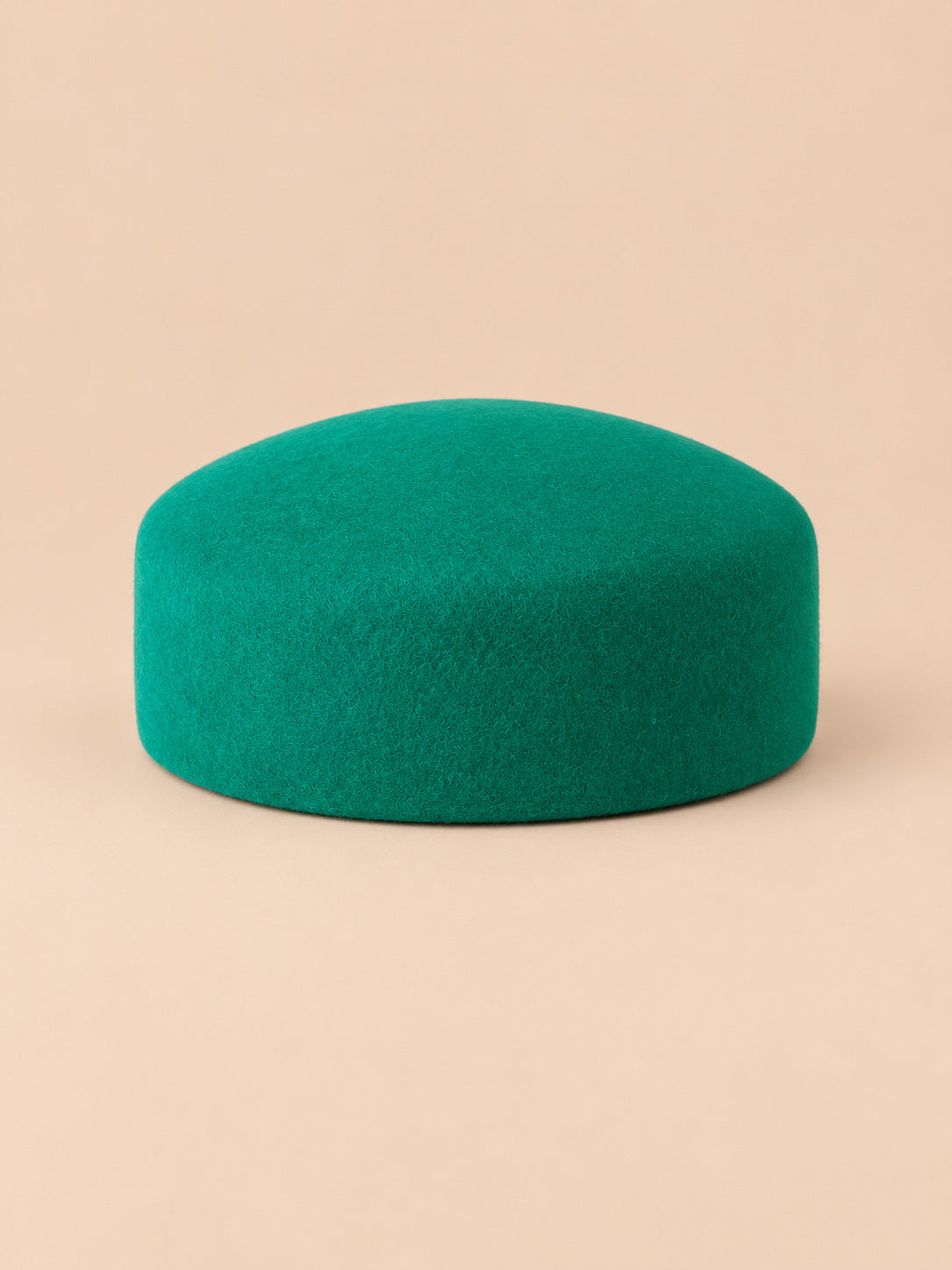 Béret femme en laine feutrée vert, forme plat, vue de face sur fond pêche sable