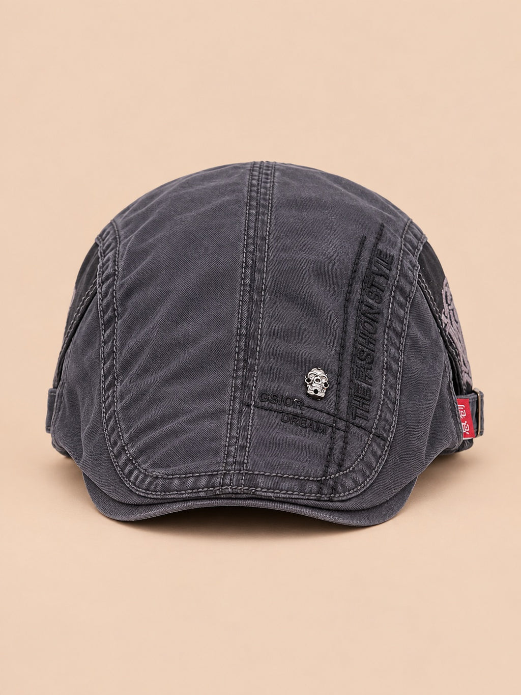 Béret gavroche en coton gris foncé, vue de face sur fond pêche sable