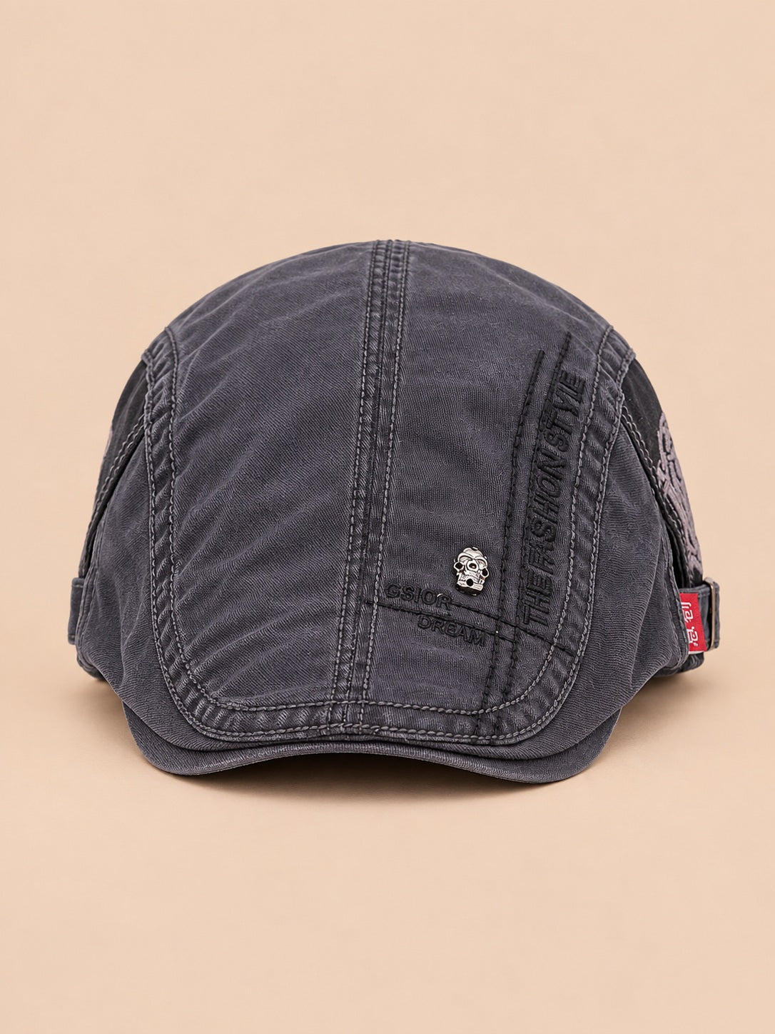 Béret gavroche en coton gris foncé, vue de face sur fond pêche sable