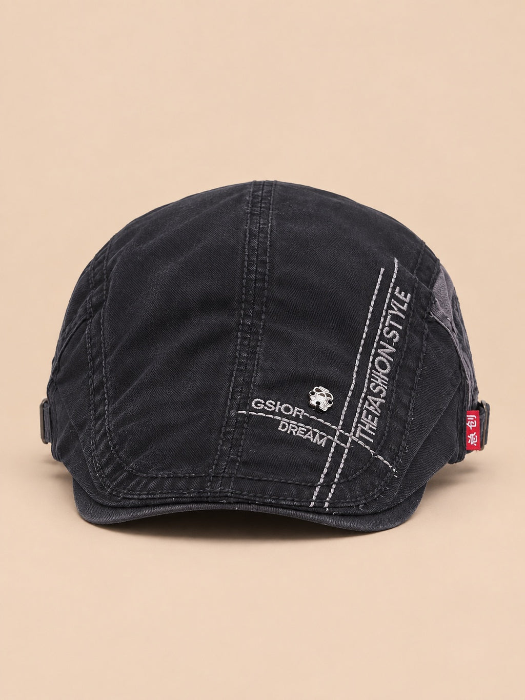 Béret gavroche en coton noir, vue de face sur fond pêche sable