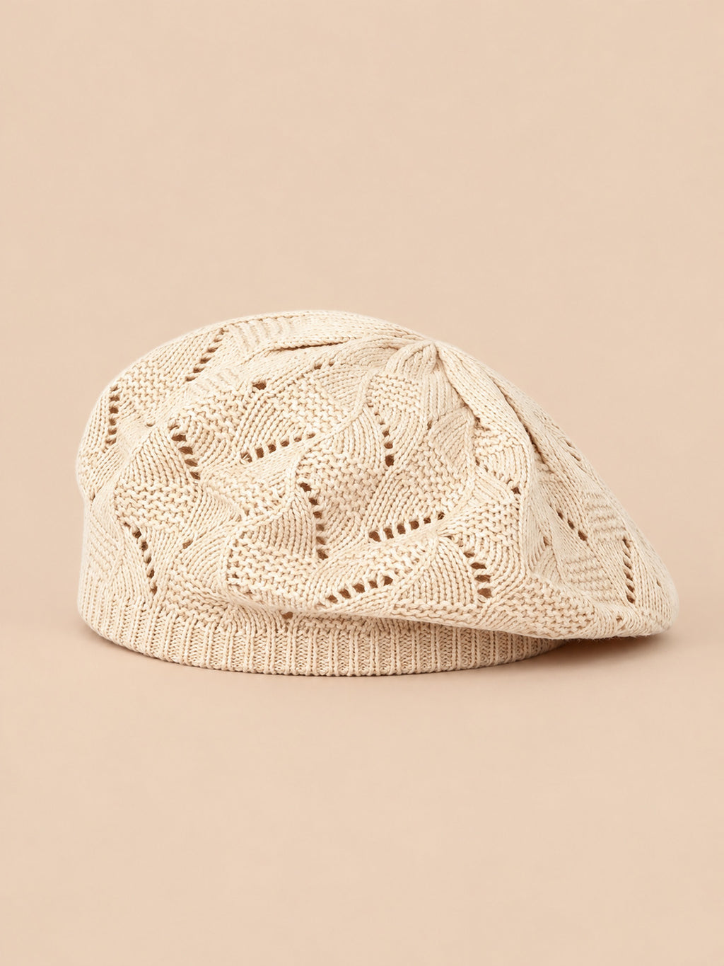 Béret plat ajouré beige, vue de face sur fond pêche sable