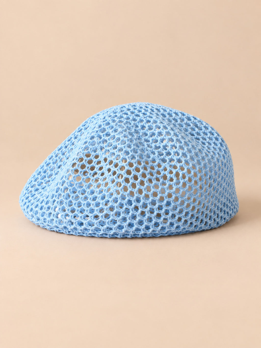 Béret résille ajouré bleu ciel, vue de face sur fond pêche sable