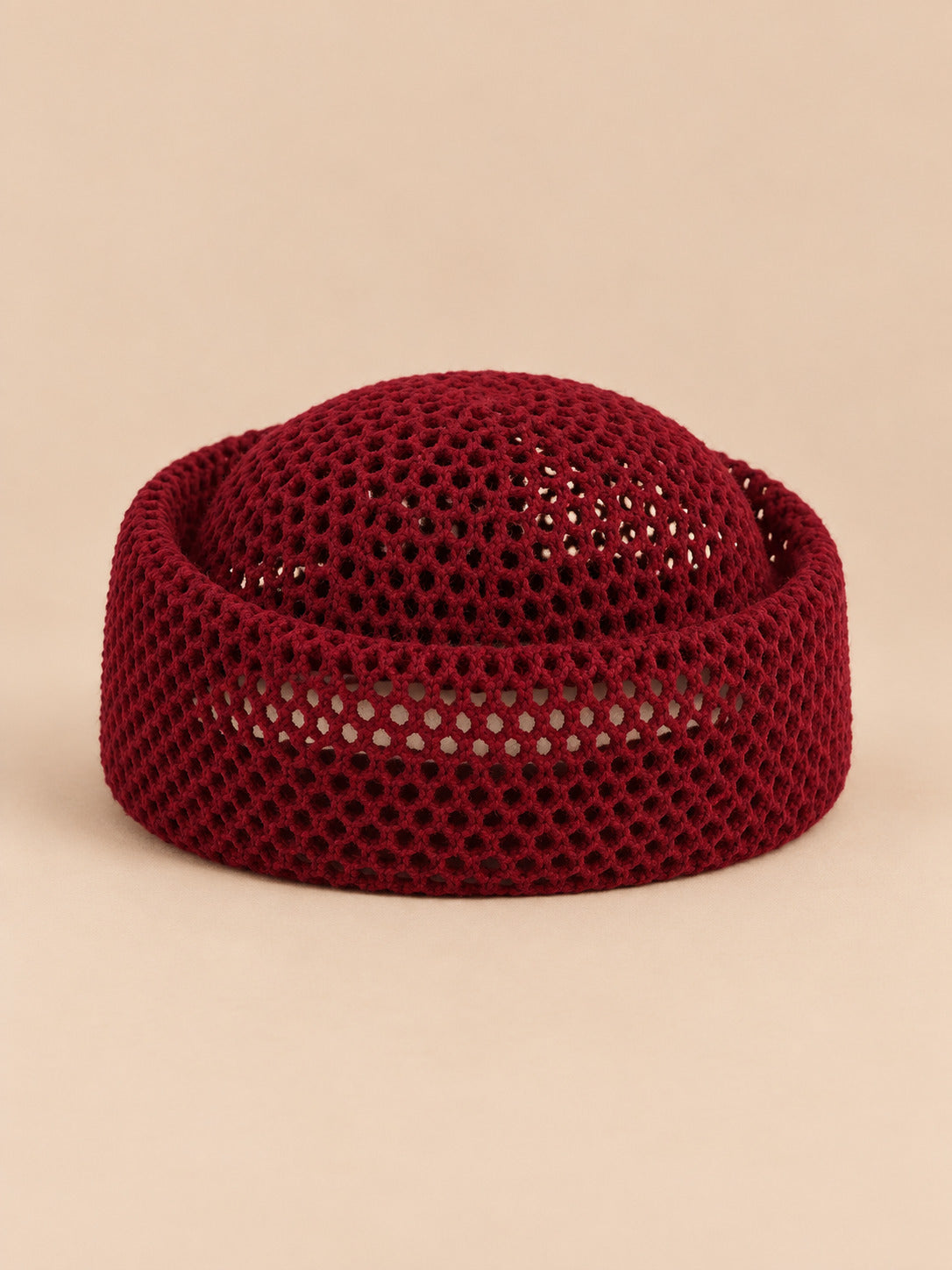 Béret résille ajouré bourgogne, vue de face sur fond pêche sable
