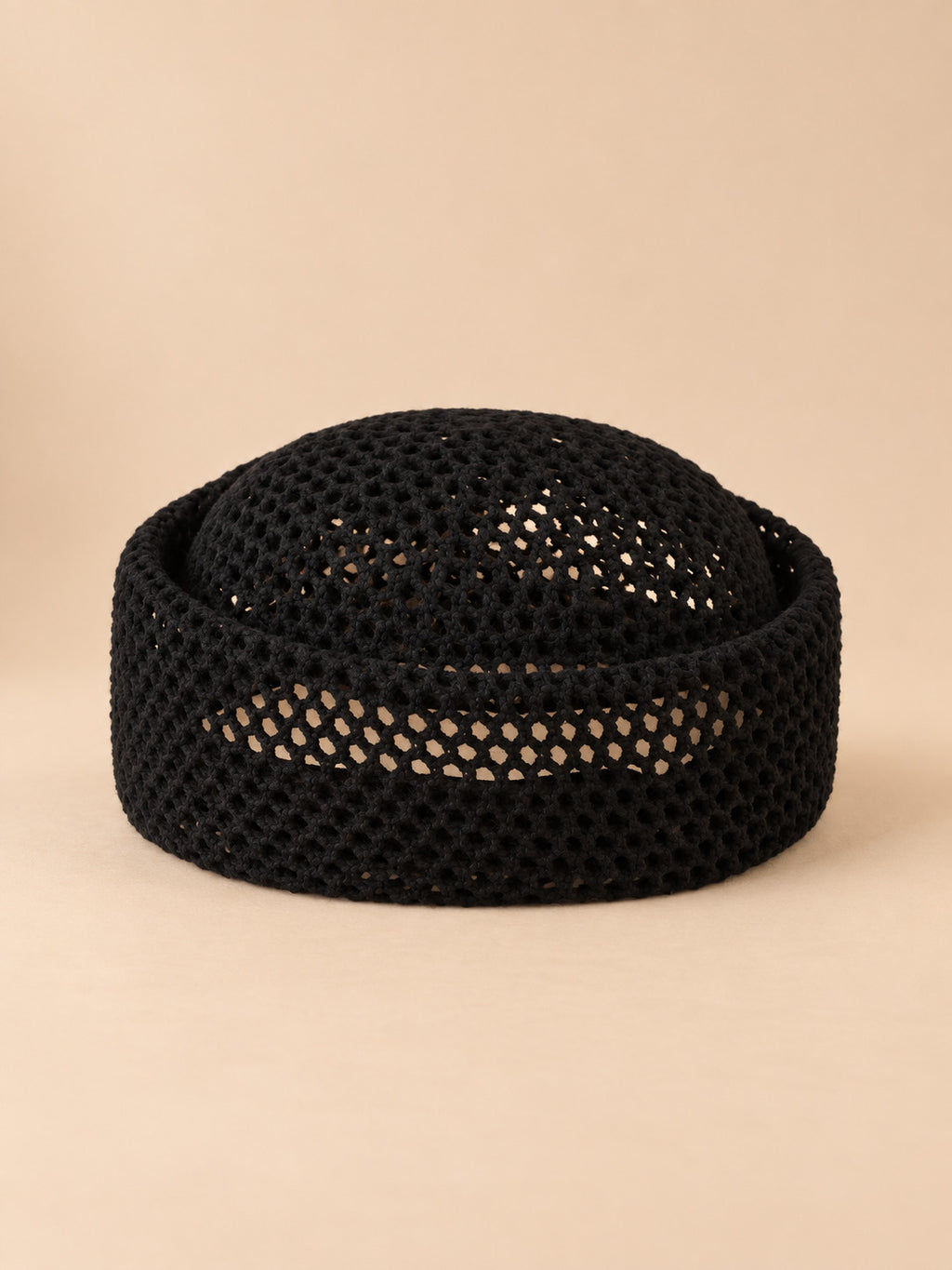 Béret résille ajouré noir 1, vue de face sur fond pêche sable