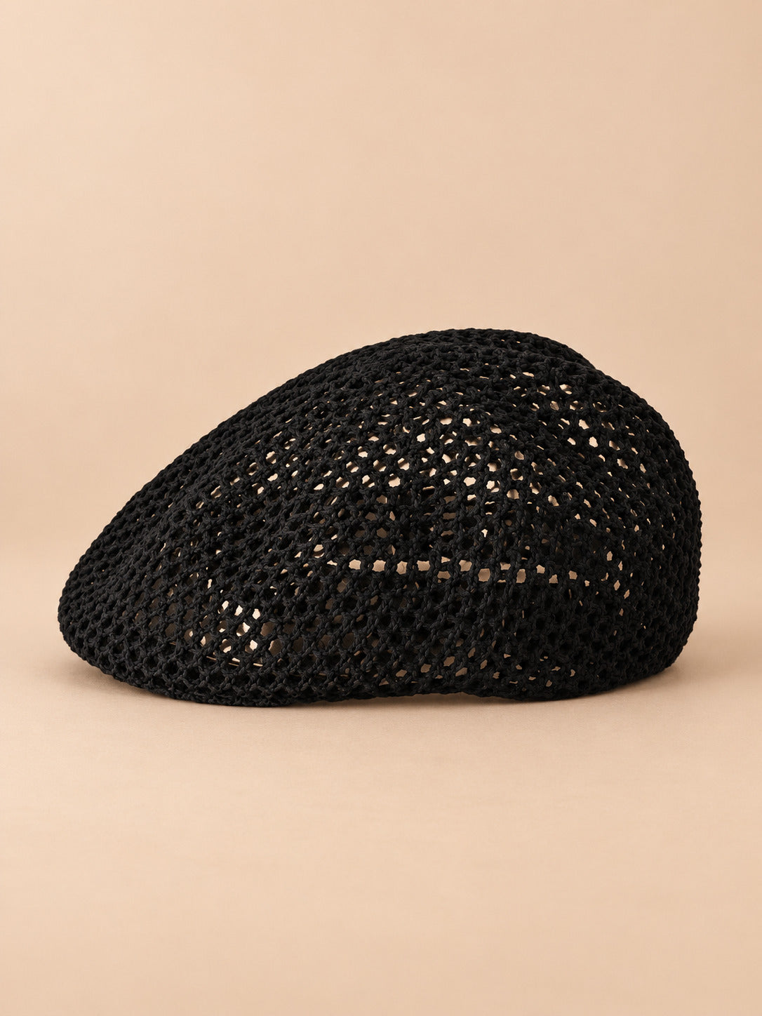 Béret résille ajouré noir, vue de face sur fond pêche sable