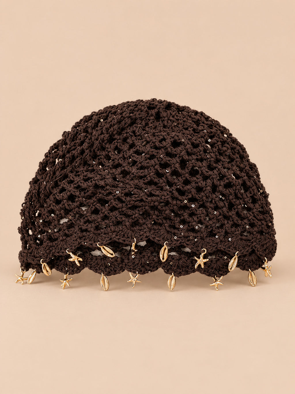 Béret rétro café ajouré au crochet à franges d'étoiles dorées, vue de face sur fond pêche sable