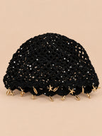 Béret rétro noir ajouré au crochet à franges d'étoiles dorées, vue de face sur fond pêche sable