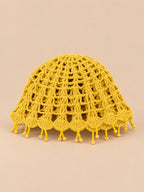 Béret crochet rétro jaune ajouré à franges de perles, vue de face sur fond pêche sable
