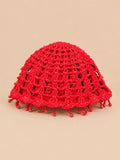 Béret crochet rétro rouge ajouré à franges de perles, vue de face sur fond pêche sable