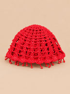 Béret crochet rétro rouge ajouré à franges de perles, vue de face sur fond pêche sable