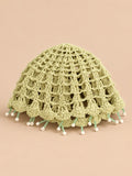 Béret crochet rétro vert ajouré à franges de perles, vue de face sur fond pêche sable