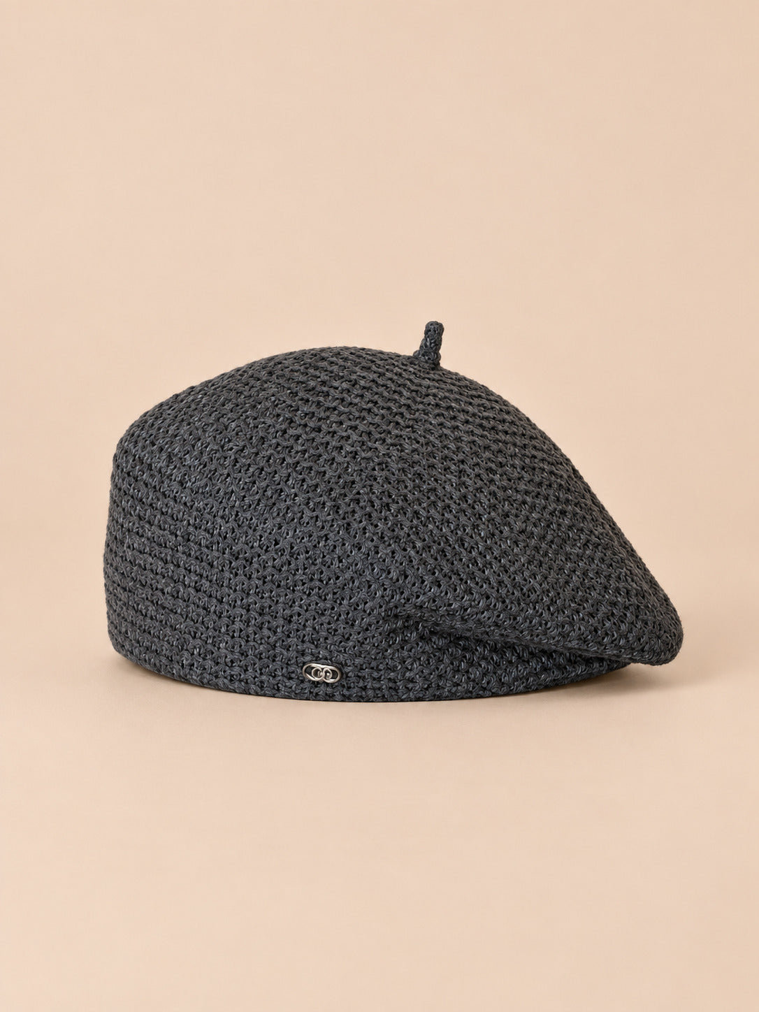 Béret tricoté ajouré léger Gris foncé, vue de face sur fond pêche sable