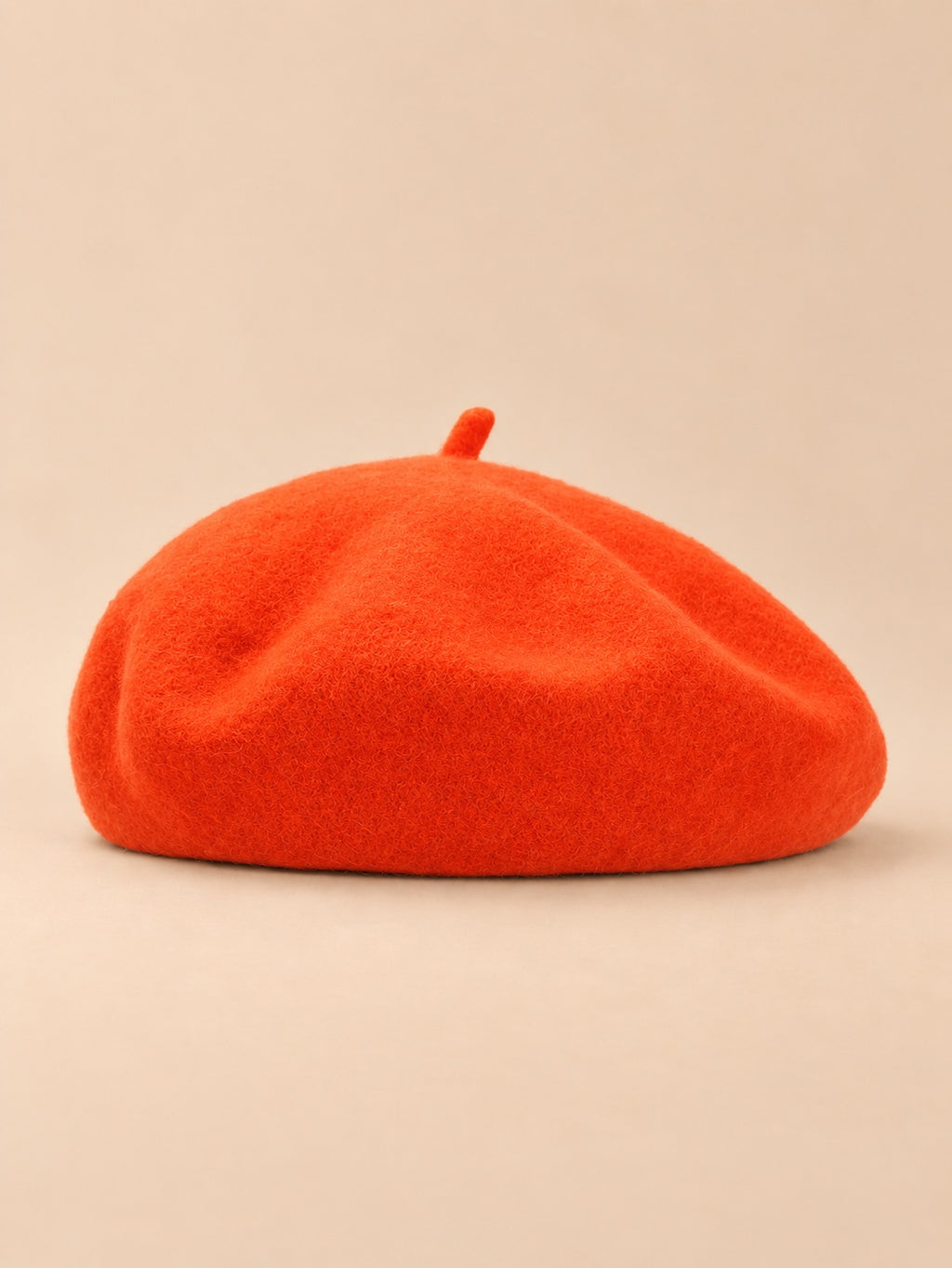 Béret uni femme en maille chaude orange, vue de face sur fond beige
