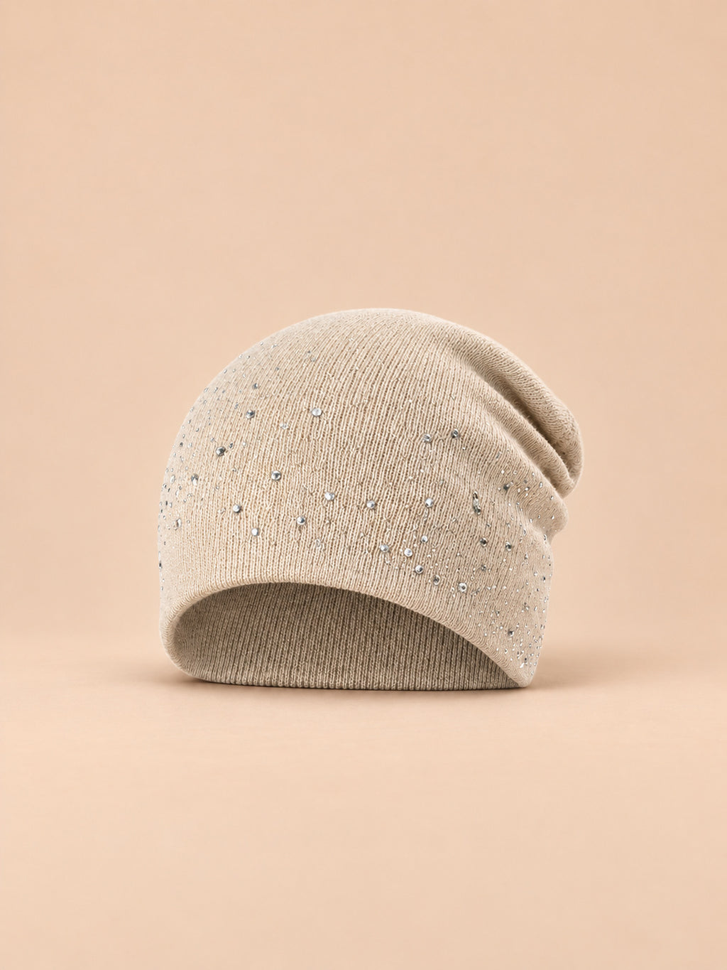 Bonnet femme tricoté à strass beige, vue de face sur fond pêche sable