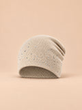 Bonnet femme tricoté à strass beige, vue de face sur fond pêche sable