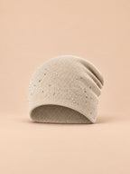 Bonnet femme tricoté à strass beige, vue de face sur fond pêche sable