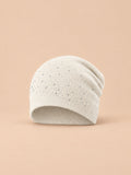 Bonnet femme tricoté à strass blanc, vue de face sur fond pêche sable