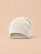Bonnet femme tricoté à strass blanc, vue de face sur fond pêche sable