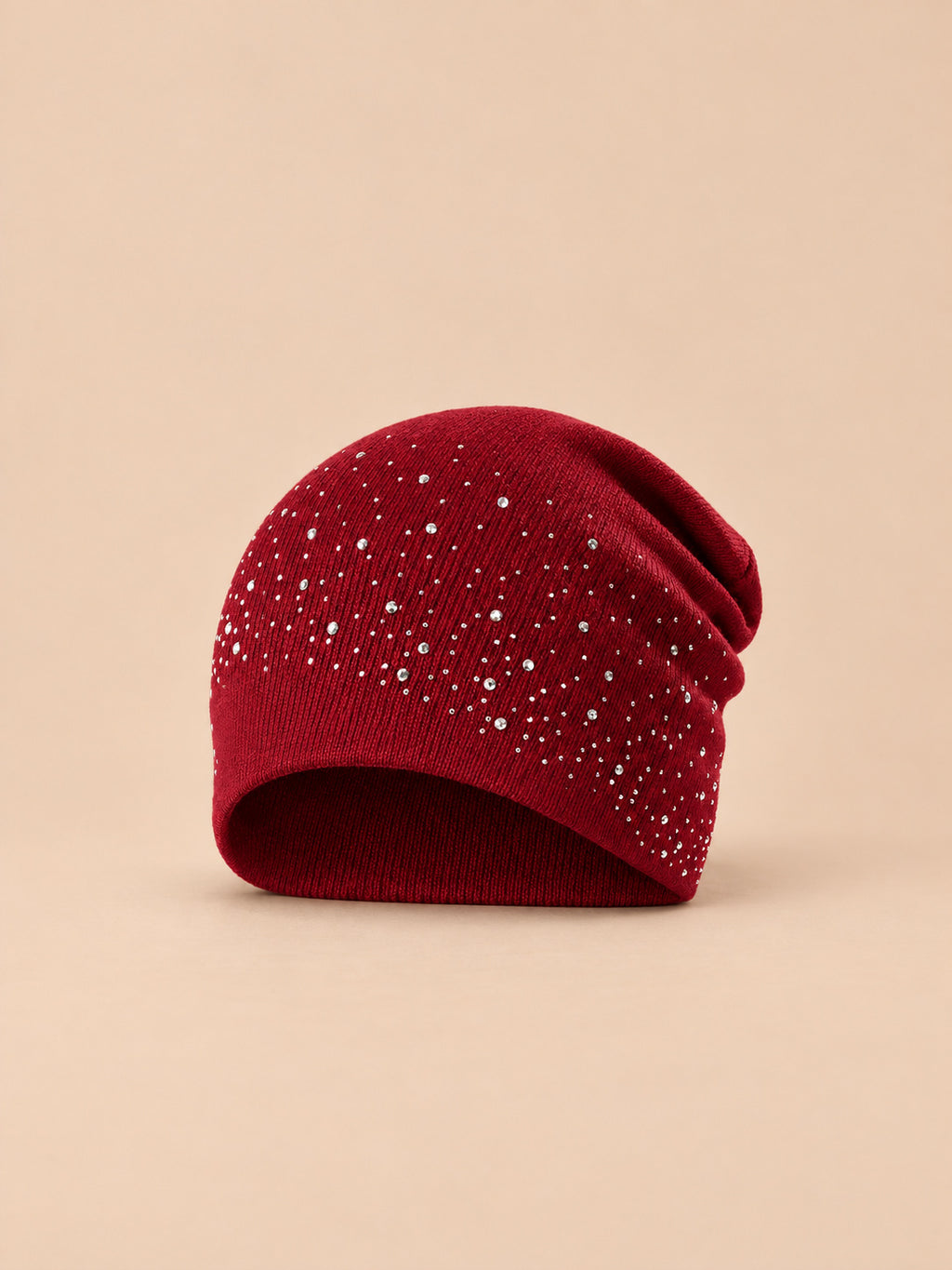 Bonnet femme tricoté à strass bordeaux, vue de face sur fond pêche sable