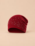 Bonnet femme tricoté à strass bordeaux, vue de face sur fond pêche sable