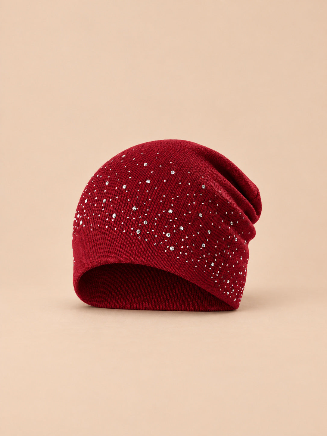Bonnet femme tricoté à strass bordeaux, vue de face sur fond pêche sable
