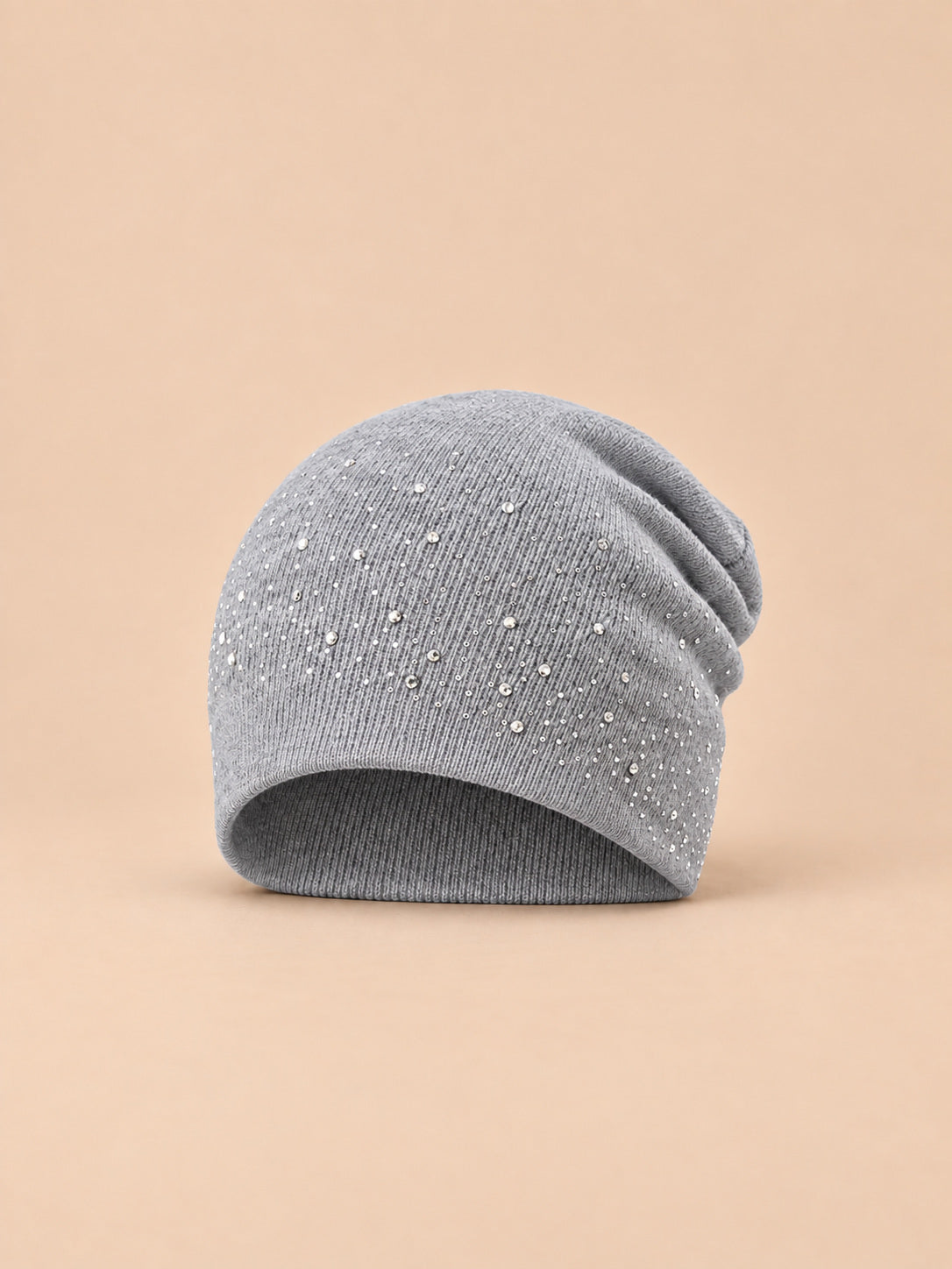 Bonnet femme tricoté à strass gris clair, vue de face sur fond pêche sable
