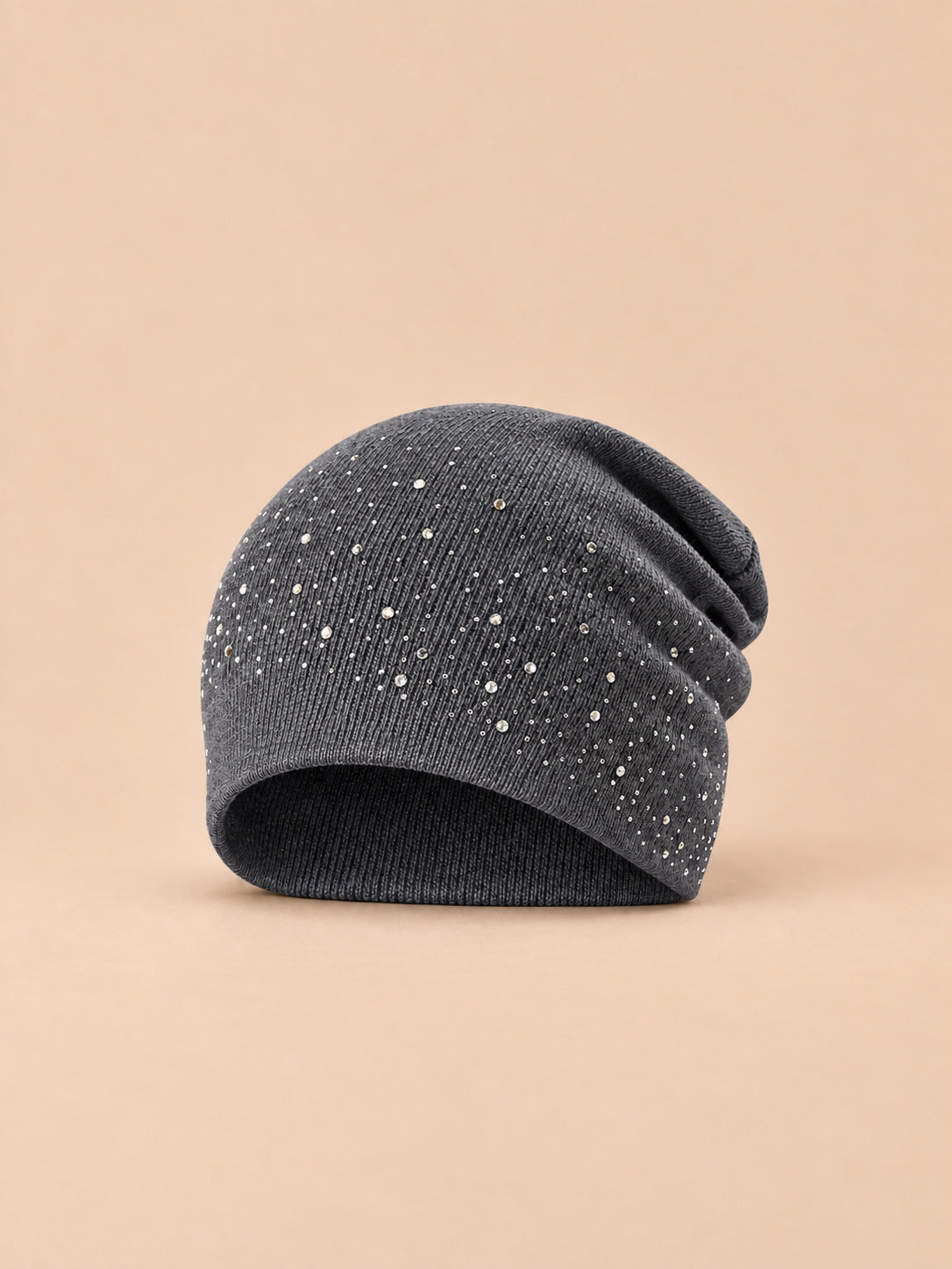 Bonnet femme tricoté à strass gris foncé, vue de face sur fond pêche sable
