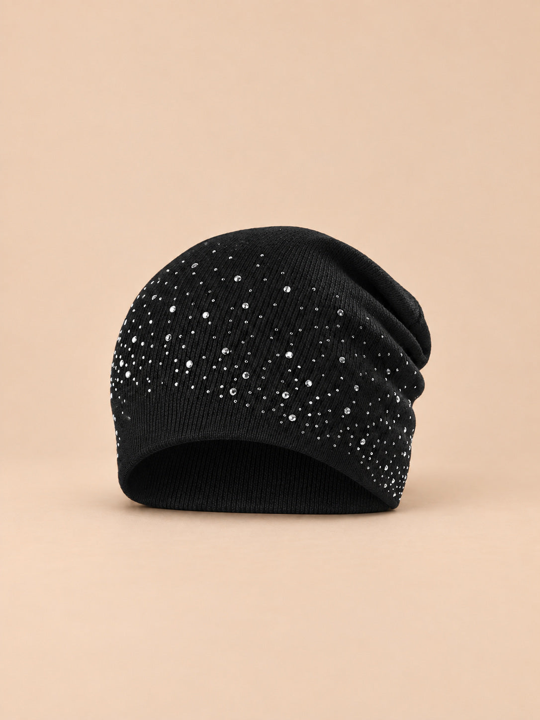 Bonnet femme tricoté à strass noir, vue de face sur fond pêche sable